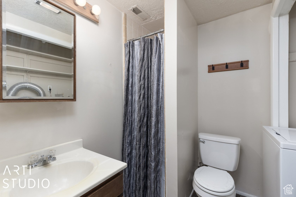 Full bath with toilet, a shower with shower curtain, a textured ceiling, vanity, and washer / clothes dryer