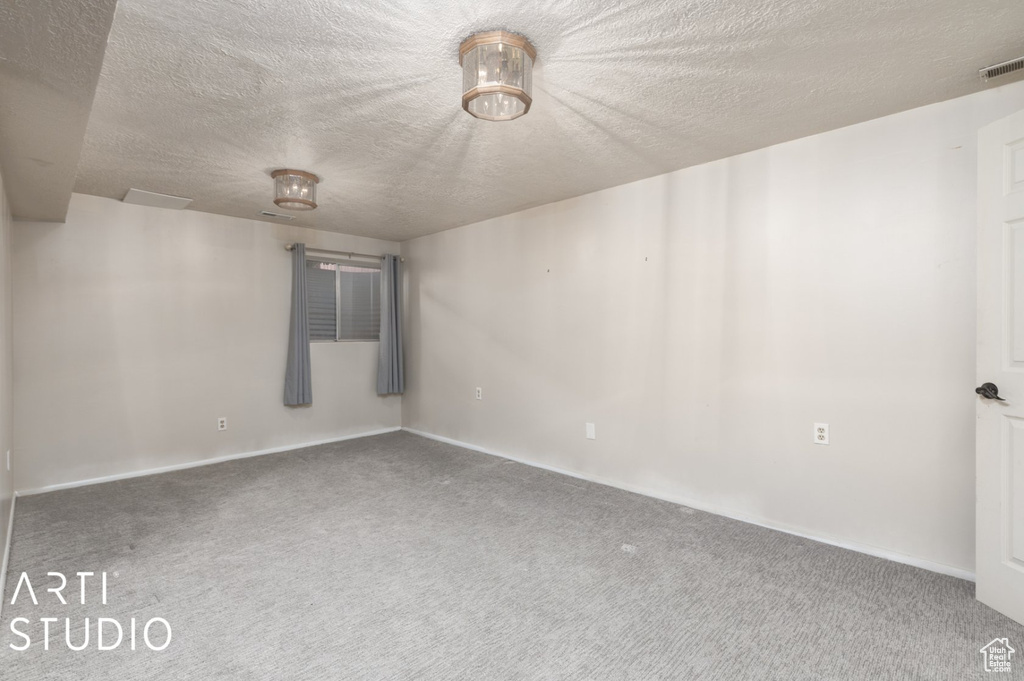 Empty room featuring baseboards, carpet flooring, visible vents, and a textured ceiling