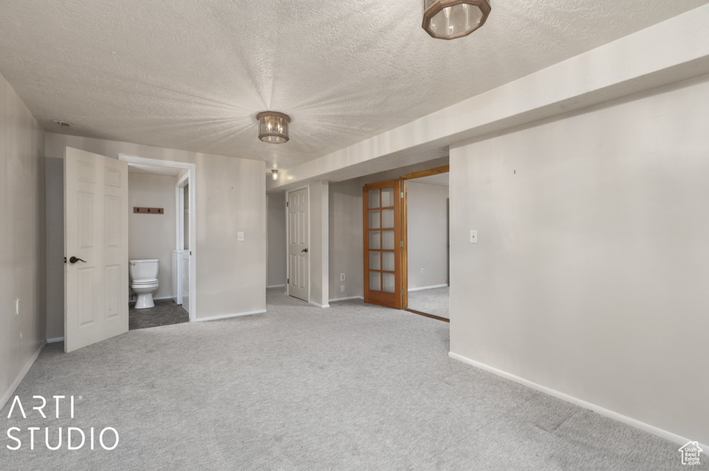 Interior space featuring a textured ceiling, connected bathroom, carpet floors, and baseboards