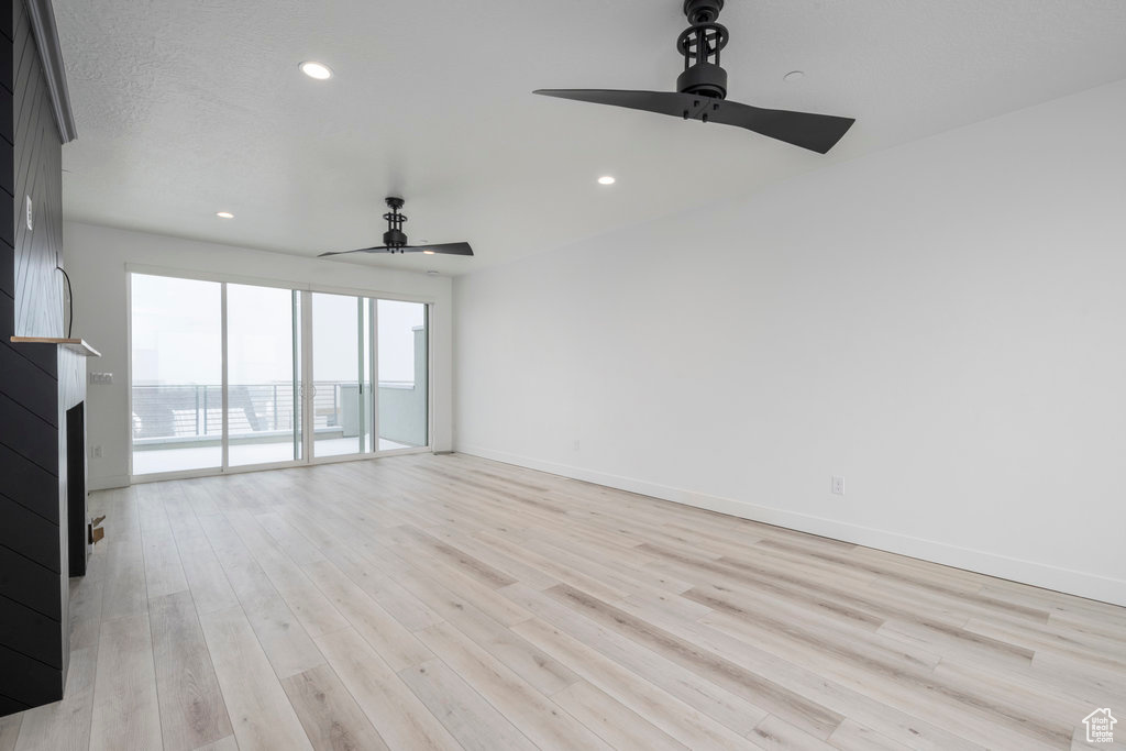 Unfurnished living room with light wood finished floors, a ceiling fan, a fireplace, baseboards, and recessed lighting