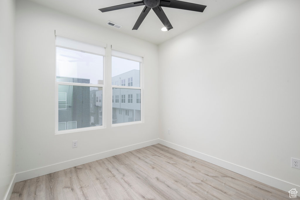 Unfurnished room featuring baseboards, a ceiling fan, visible vents, and wood finished floors
