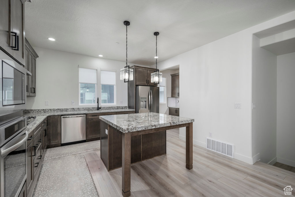 Kitchen featuring dark brown cabinets, light wood-style flooring, a sink, stainless steel appliances, and visible vents