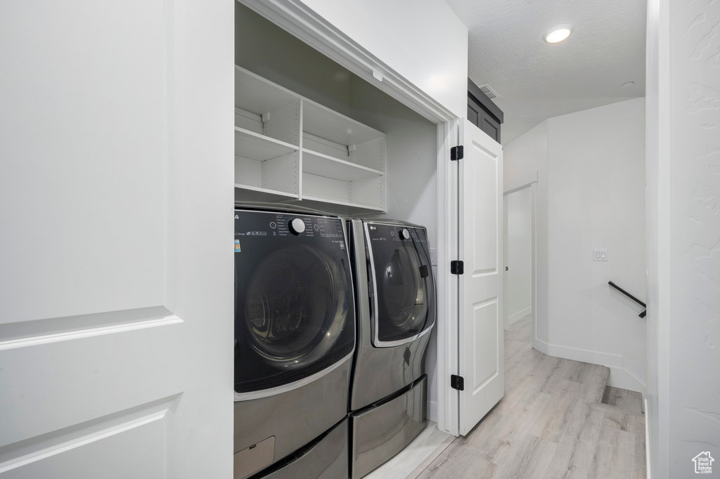Clothes washing area with laundry area, independent washer and dryer, and light wood-style floors