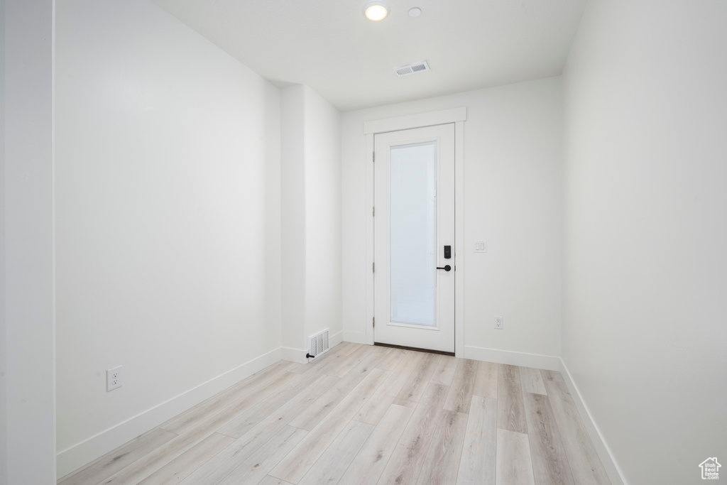 Spare room with light wood-style floors, visible vents, and baseboards