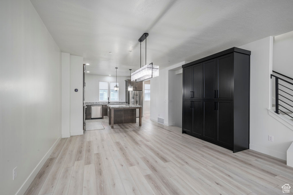 Kitchen with visible vents, light wood finished floors, dark cabinetry, baseboards, and appliances with stainless steel finishes
