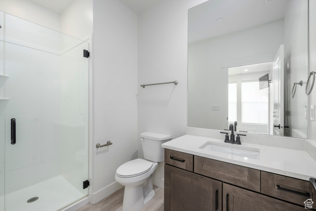 Full bath featuring a stall shower, vanity, toilet, and wood finished floors