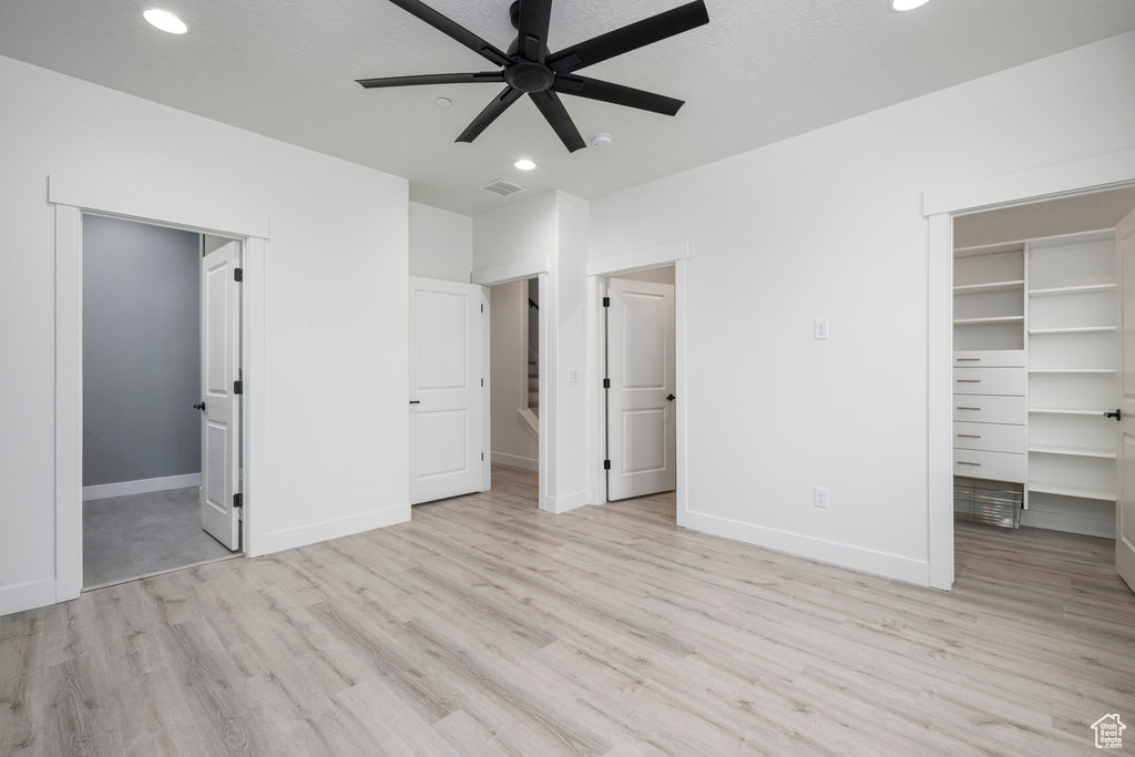 Unfurnished bedroom featuring wood finished floors, visible vents, baseboards, a spacious closet, and recessed lighting