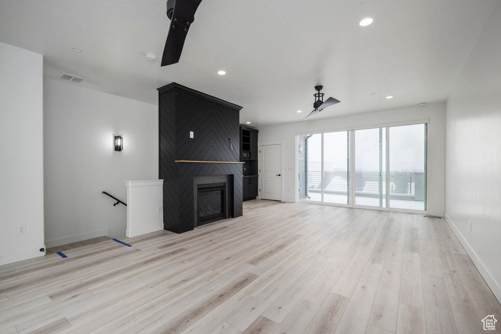Unfurnished living room featuring visible vents, recessed lighting, a large fireplace, baseboards, and light wood-style floors