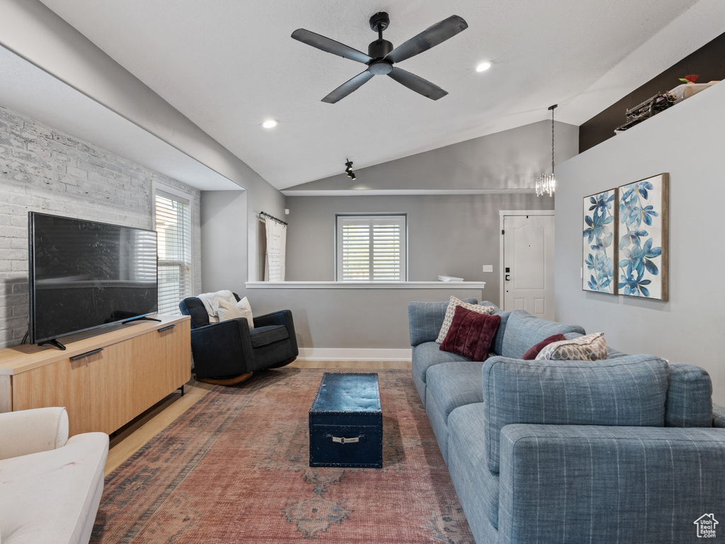 Living room with baseboards, ceiling fan with notable chandelier, recessed lighting, and lofted ceiling