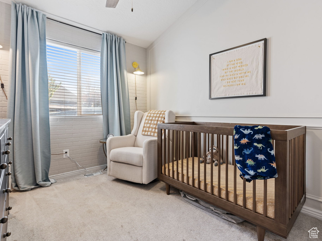 Carpeted bedroom featuring a nursery area, ceiling fan, and lofted ceiling