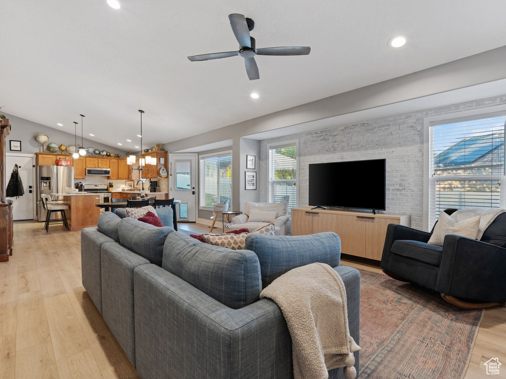 Living room featuring light wood-style floors, a ceiling fan, vaulted ceiling, and recessed lighting