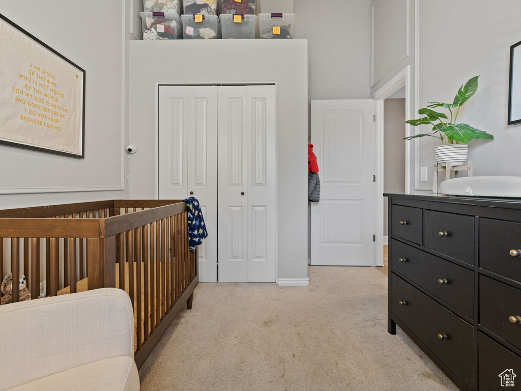 Bedroom with light colored carpet and a closet