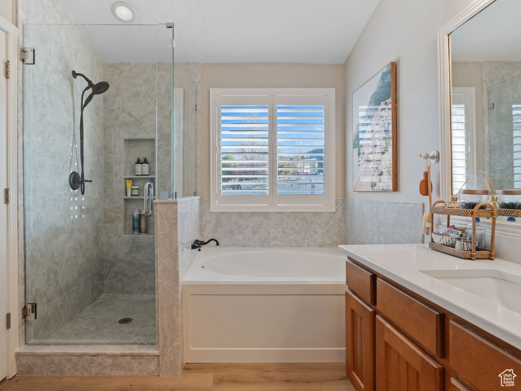 Bathroom with a shower stall, wood finished floors, a bath, and vanity