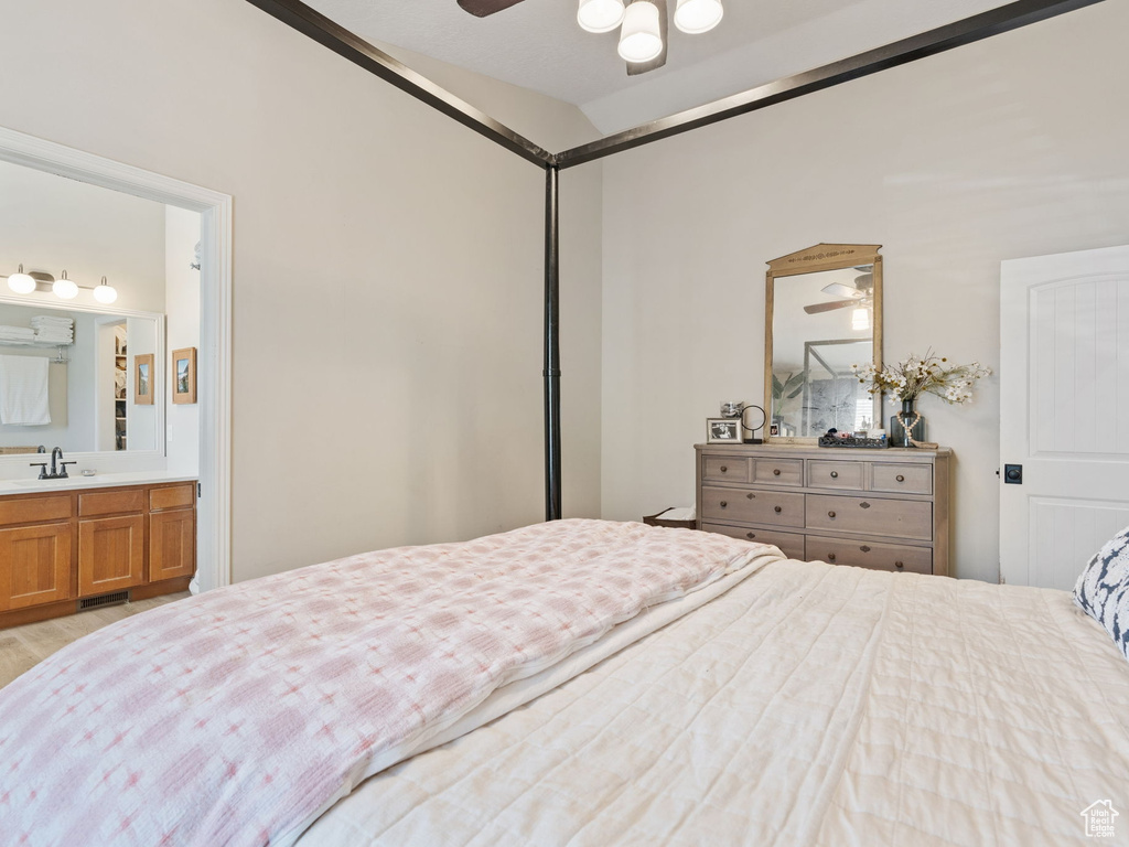Bedroom with lofted ceiling, a sink, ensuite bathroom, and wood finished floors