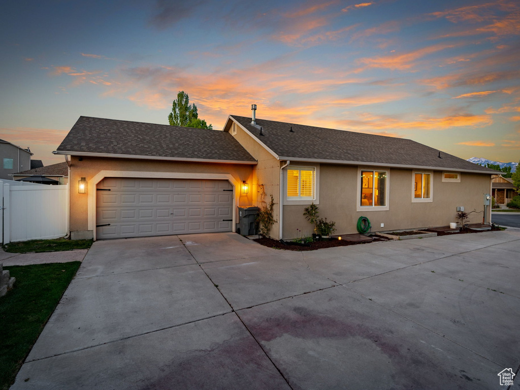 Ranch-style house featuring a gate, an attached garage, driveway, and stucco siding
