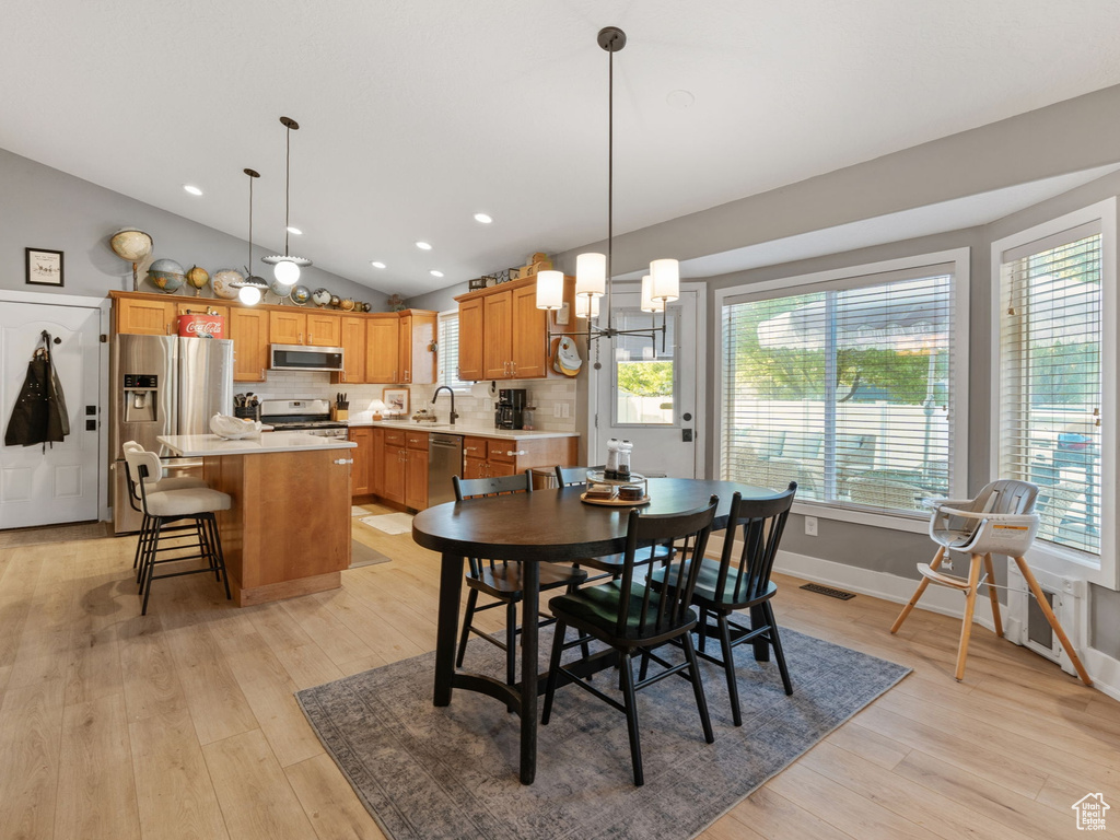 Dining area featuring an inviting chandelier, light wood-style floors, recessed lighting, vaulted ceiling, and visible vents