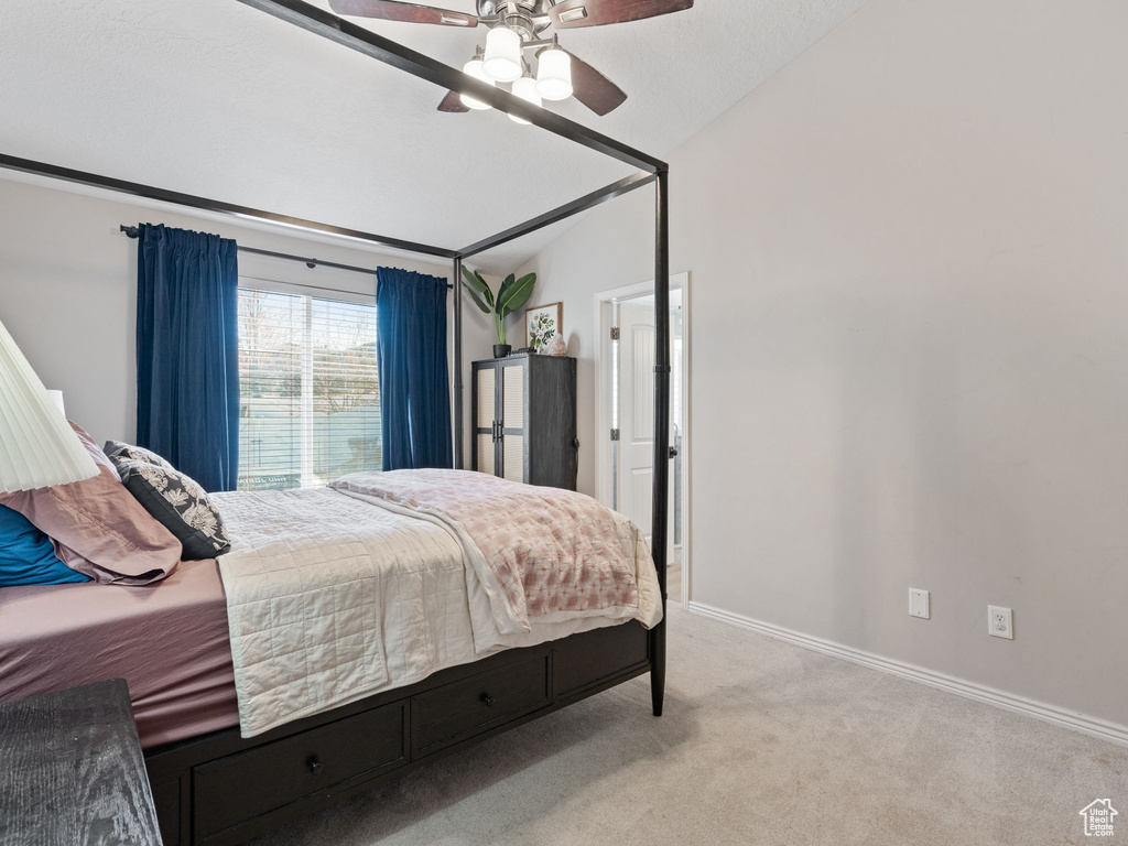 Bedroom featuring baseboards, vaulted ceiling, light carpet, and ceiling fan