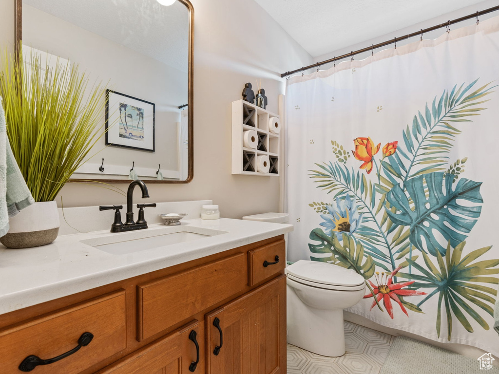Bathroom with vanity, toilet, and curtained shower