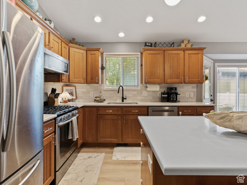 Kitchen featuring appliances with stainless steel finishes, a sink, light wood finished floors, light countertops, and recessed lighting