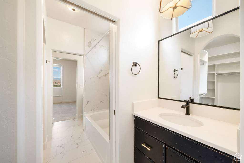 Full bathroom featuring marble finish floor, vanity, and plenty of natural light