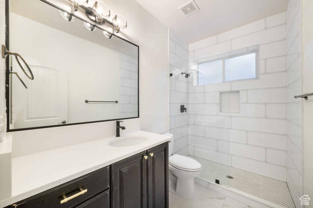 Bathroom with toilet, marble finish floor, visible vents, tiled shower, and vanity