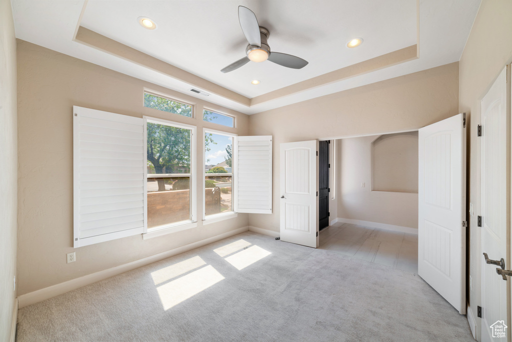 Unfurnished bedroom featuring recessed lighting, baseboards, visible vents, a raised ceiling, and light carpet