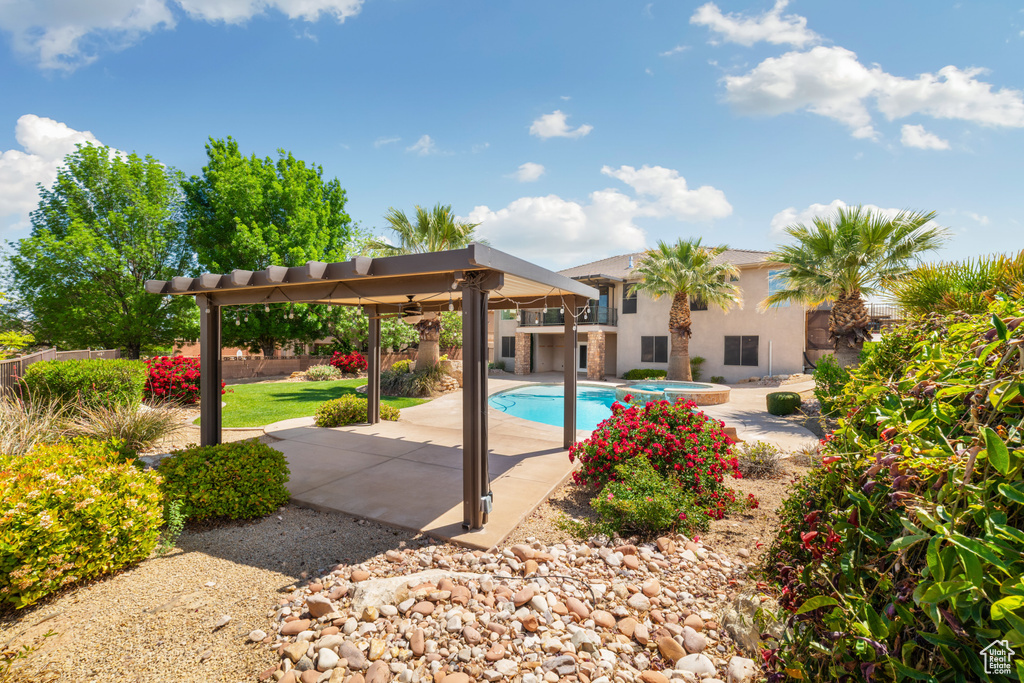 Outdoor pool featuring a ceiling fan, an in ground hot tub, fence, and a patio