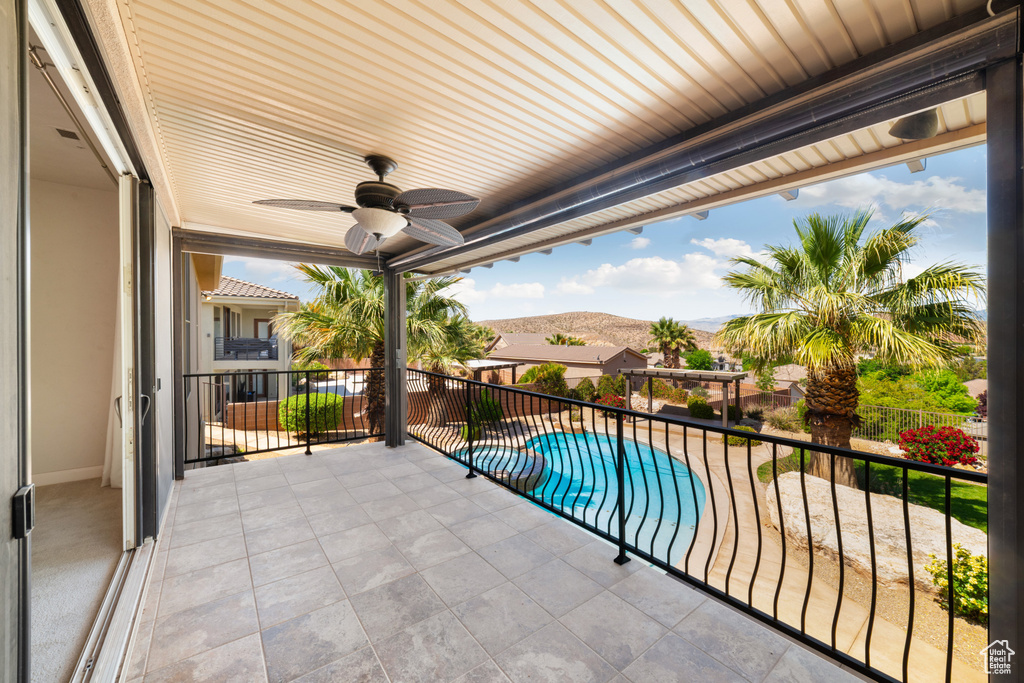 Balcony with a mountain view, a pool with connected hot tub, and a ceiling fan