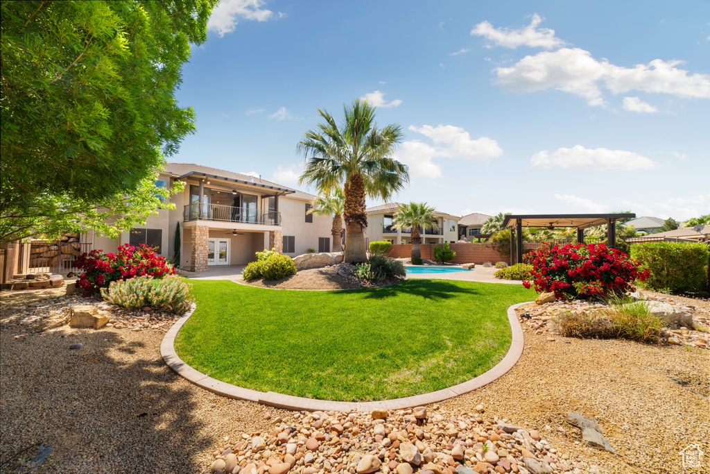 View of yard with french doors, a ceiling fan, fence, a balcony, and a fenced in pool