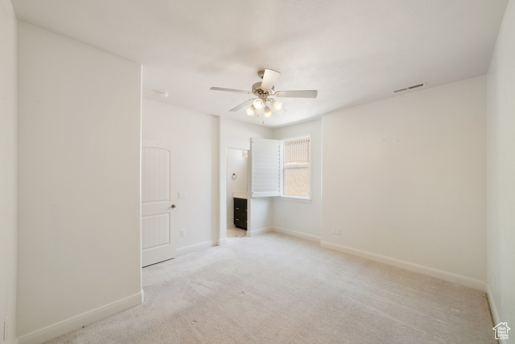 Spare room with light colored carpet, baseboards, a ceiling fan, and visible vents