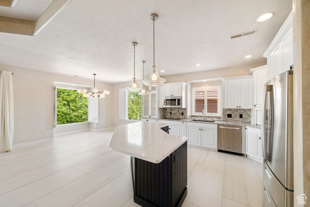 Kitchen featuring white cabinetry, decorative backsplash, visible vents, and appliances with stainless steel finishes