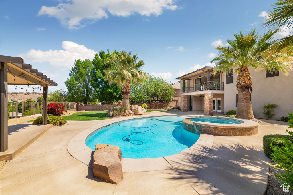 View of swimming pool with a patio, a pool with connected hot tub, and a fenced backyard