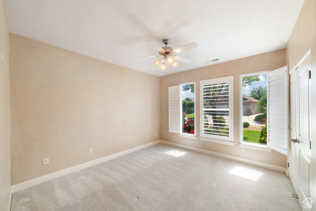 Carpeted empty room featuring baseboards, a ceiling fan, and visible vents