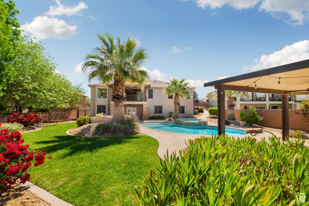 View of swimming pool featuring a yard, a fenced backyard, a patio, and a pool with connected hot tub