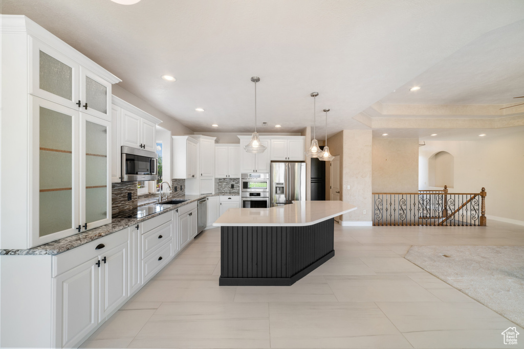 Kitchen featuring a center island, white cabinets, backsplash, appliances with stainless steel finishes, and recessed lighting