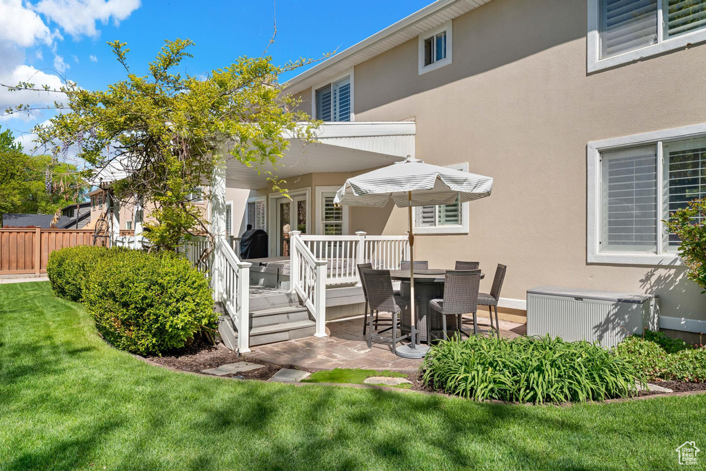 Back of house featuring a lawn, fence, stucco siding, and a patio area