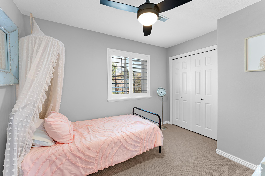 Carpeted bedroom featuring a ceiling fan, baseboards, and a closet