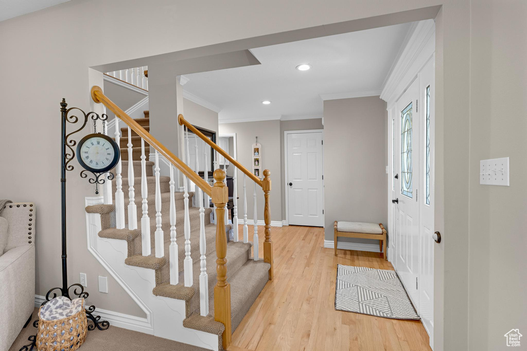 Foyer entrance featuring crown molding, baseboards, stairs, and wood finished floors