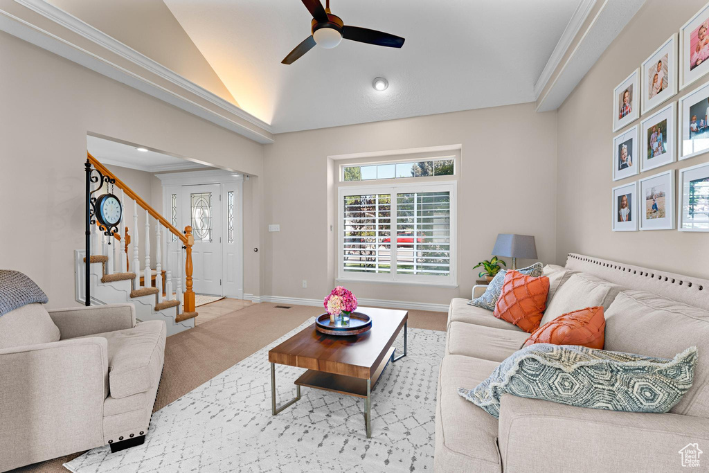 Living area featuring stairs, baseboards, ceiling fan, carpet, and vaulted ceiling