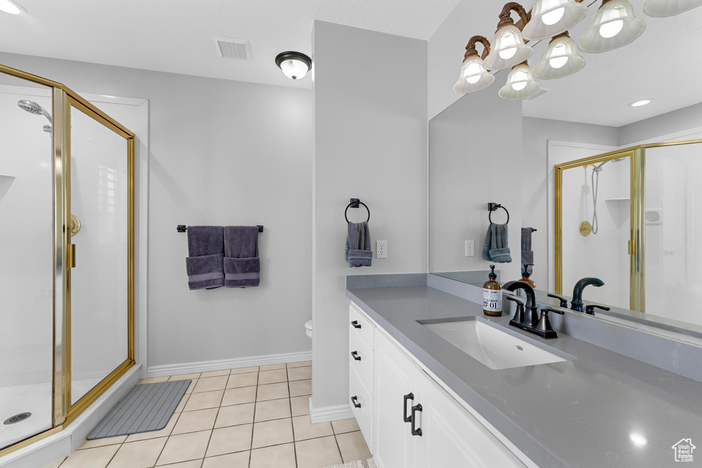 Full bath with a chandelier, a shower stall, and tile patterned flooring