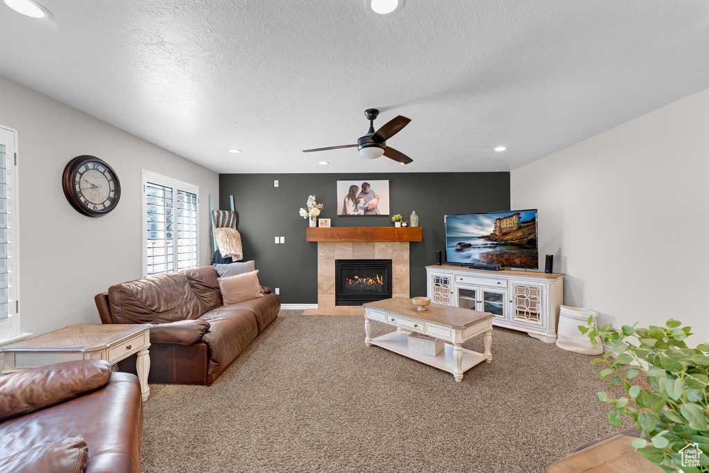 Carpeted living area featuring a textured ceiling, a ceiling fan, recessed lighting, and a tile fireplace