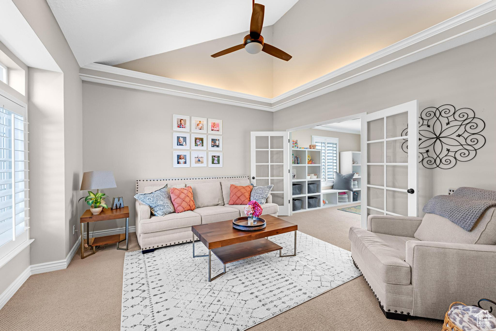 Living area with a ceiling fan, vaulted ceiling, a wealth of natural light, and light carpet