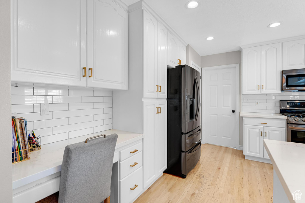 Kitchen featuring white cabinets, appliances with stainless steel finishes, light wood-style floors, recessed lighting, and backsplash