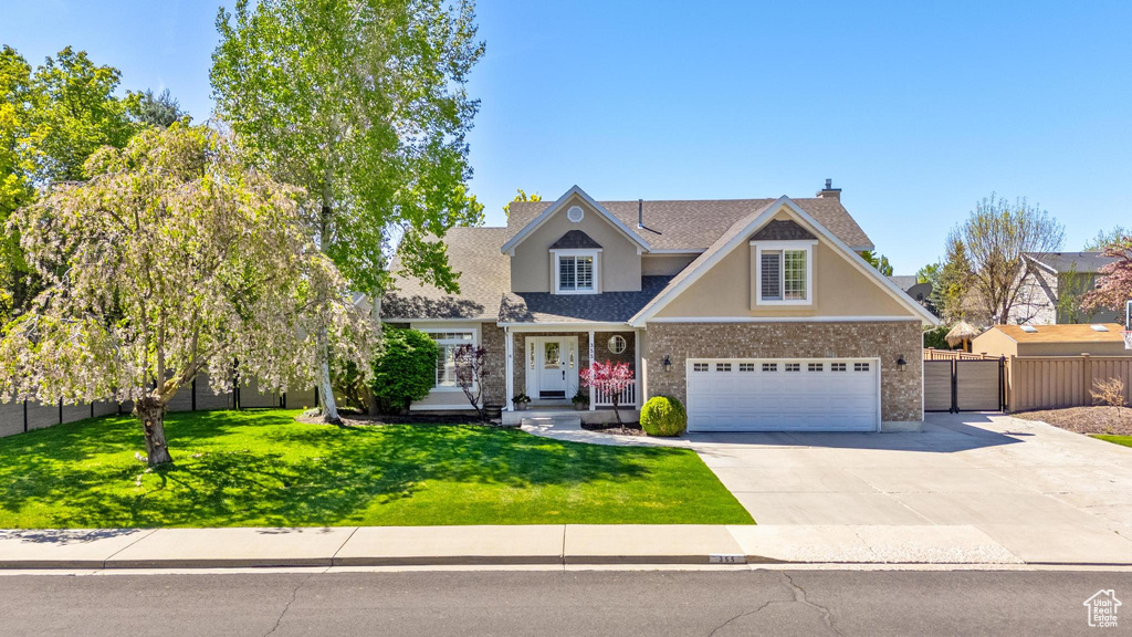 Craftsman inspired home with a garage, fence, a front yard, stucco siding, and driveway
