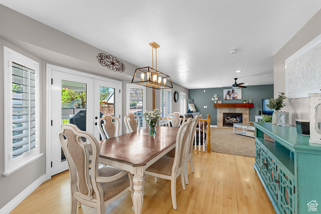 Dining area featuring a healthy amount of sunlight, a ceiling fan, light wood-type flooring, and a tile fireplace