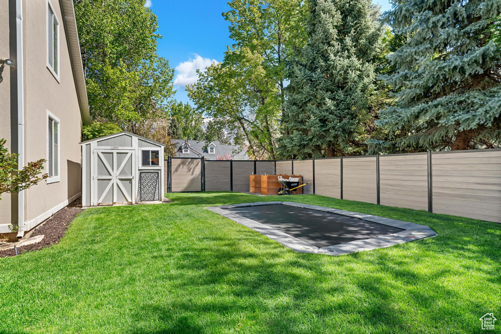 View of yard featuring a fenced backyard, a storage unit, an outbuilding, and a patio area