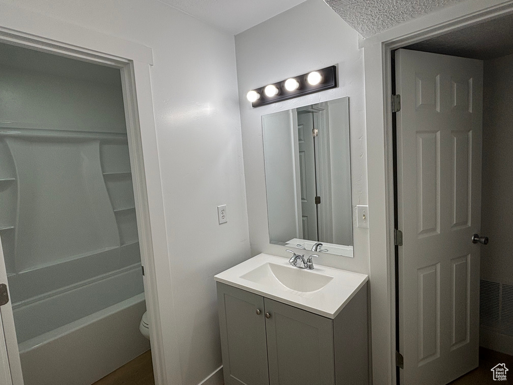 Full bath featuring vanity, toilet, a textured ceiling, and bathtub / shower combination