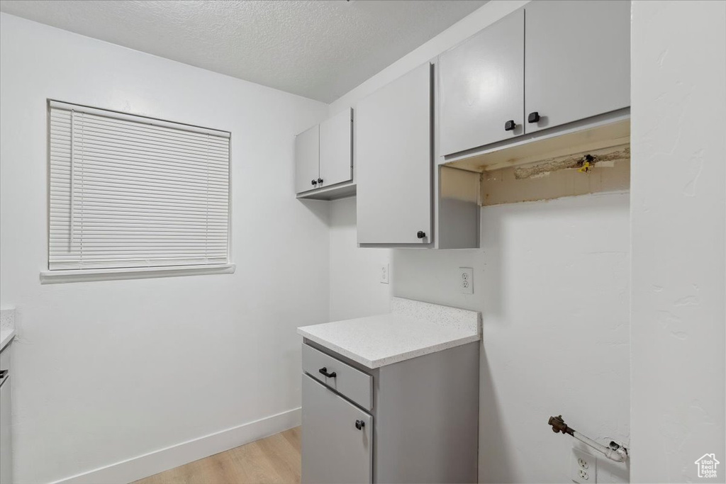 Washroom with light wood-style floors, a textured ceiling, and baseboards