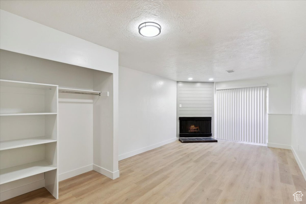 Unfurnished living room featuring baseboards, a textured ceiling, and wood finished floors