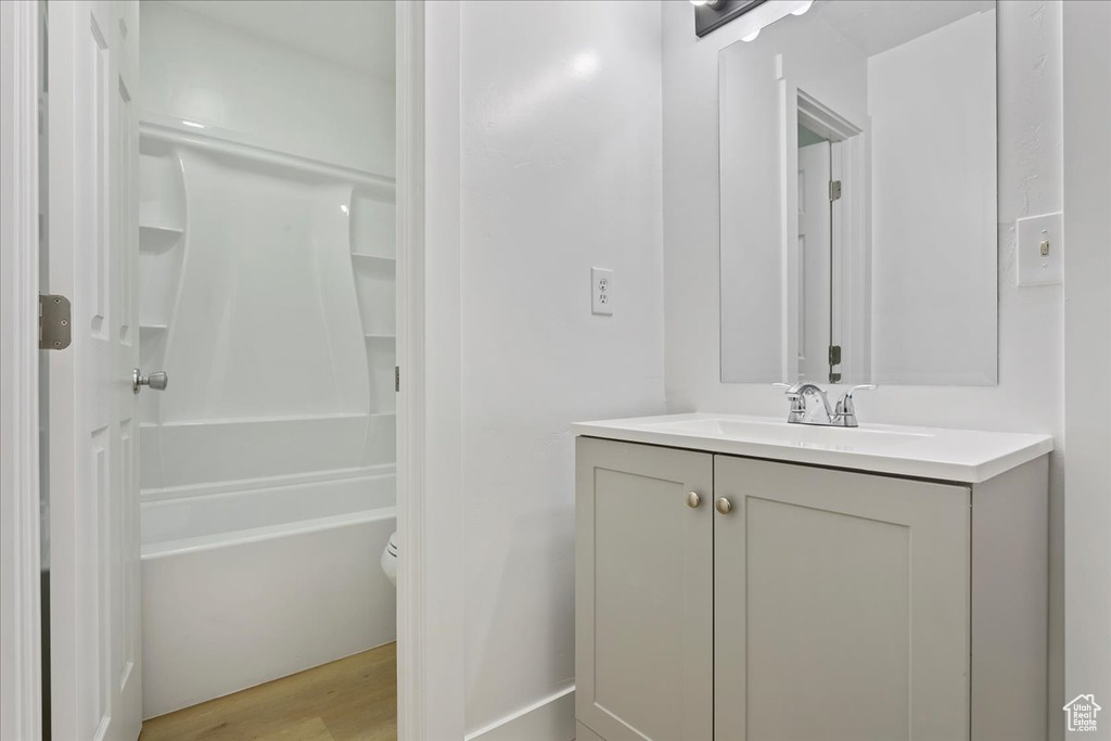 Full bathroom with vanity, wood finished floors, toilet, and shower / washtub combination